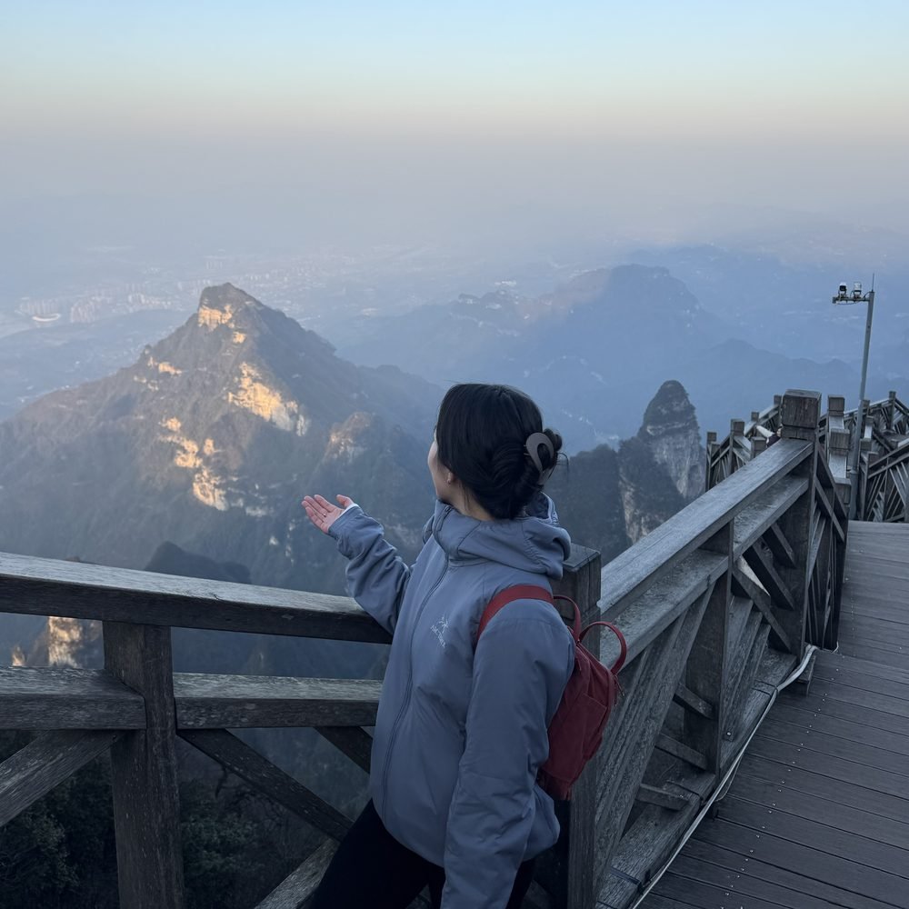 Stephanie at a mountain overlook at dusk, facing away toward misty peaks